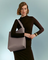 Woman posing with a handbag, her arms crossed in front of her.