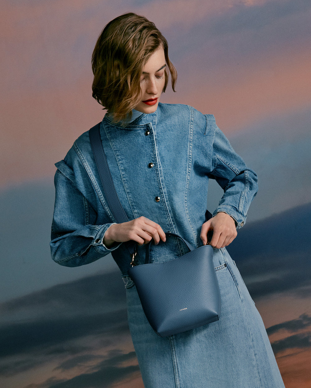 Woman in long sleeve shirt holding a handbag.