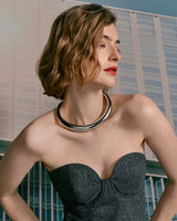 Woman wearing a strapless top and a choker, looking to the side.