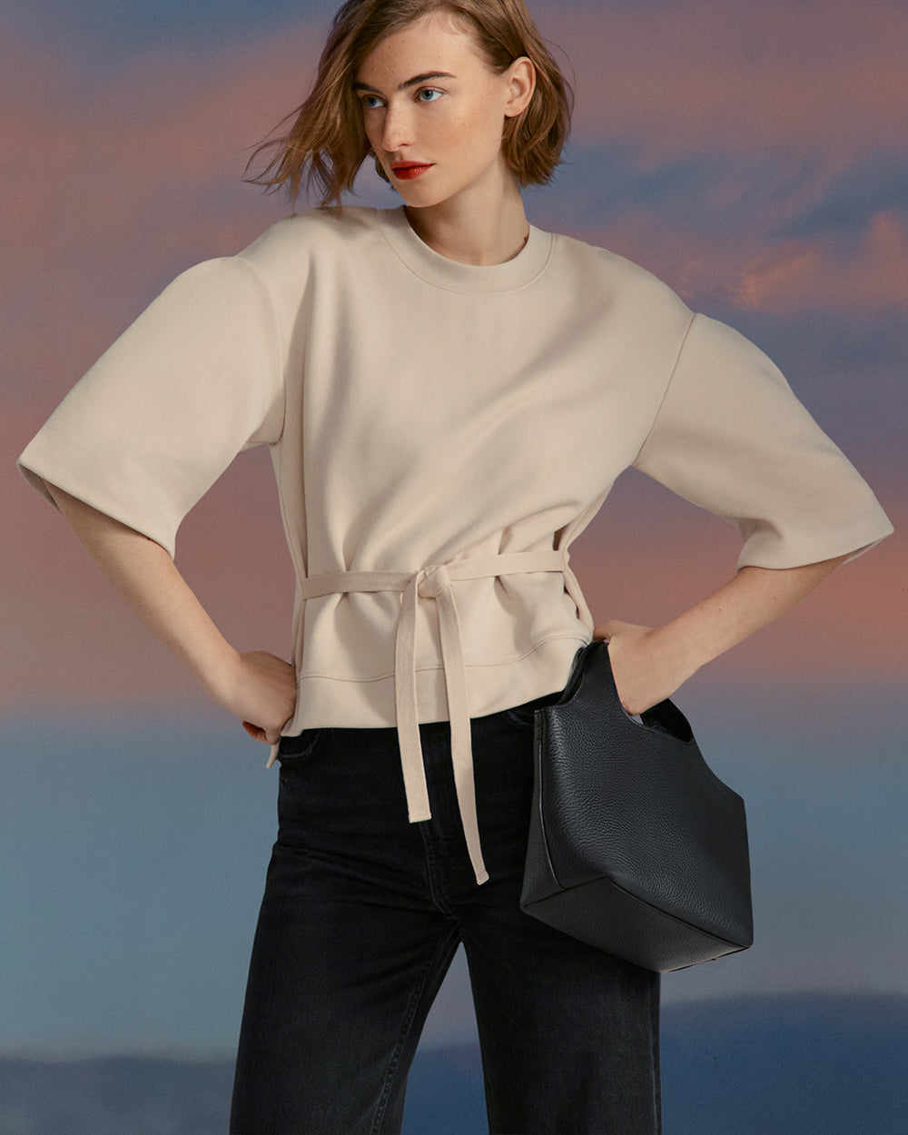 Terry Sculpted Sleeve Sweatshirt Woman standing with hands on hips holding a bag.