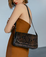 Woman wearing dress with shoulder bag featuring snake pattern.