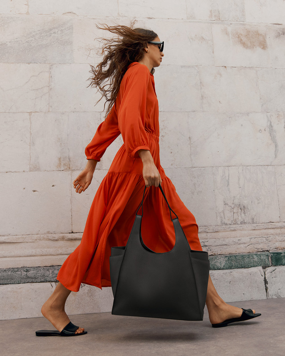 Woman walking briskly holding a large bag