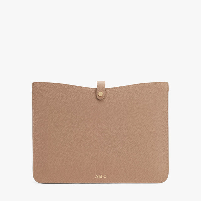 Leather clutch with a front flap and button closure, monogrammed with initials ABC at the bottom center.