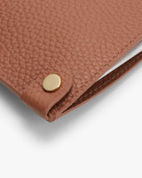 Laptop covered with a textured sleeve, partial view with a snap closure.