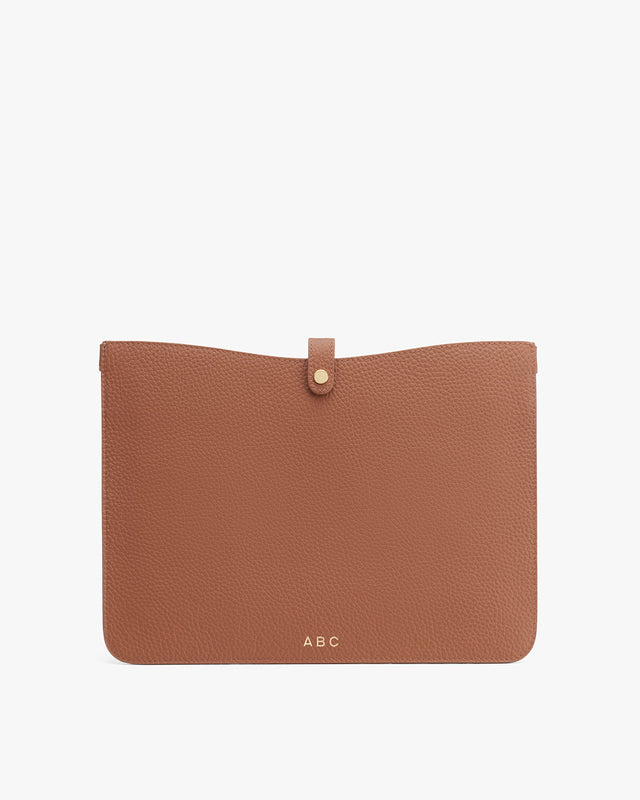 Closed leather clutch with initials ABC on the bottom right corner.