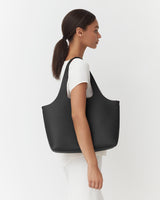 Woman carrying a large handbag on her shoulder, viewed from the side.