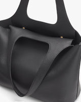 Close-up of a textured tote bag with exterior pockets.