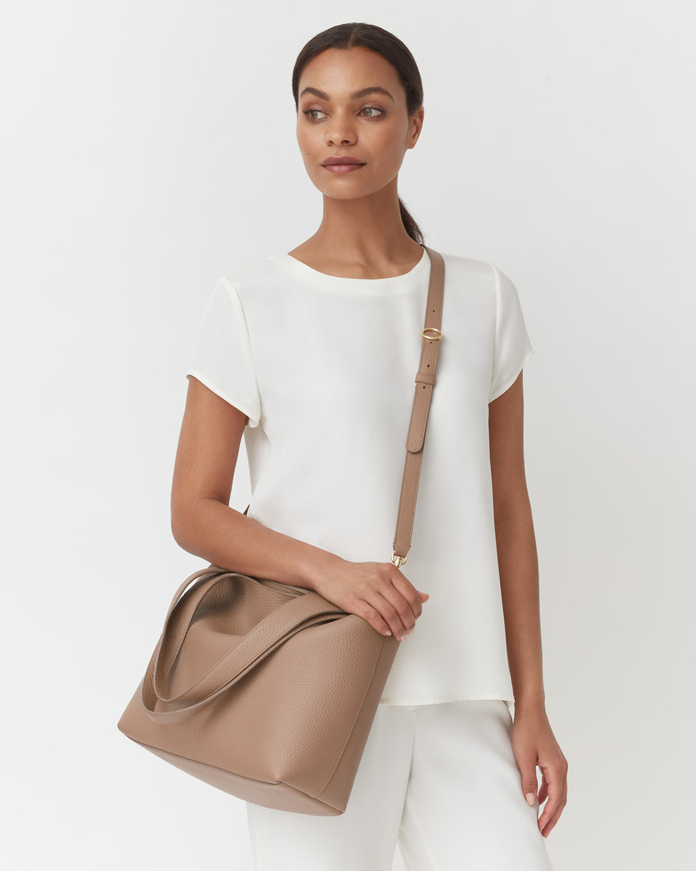 Woman standing with a handbag on her shoulder.