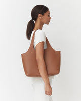Woman in a white top carrying a large tote bag