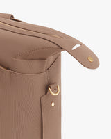 Close-up of a travel bag corner with zipper and button details.