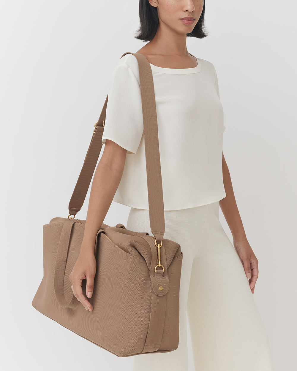 Weekender Bag (Recycled Knit) Person carrying a travel bag over shoulder wearing a short-sleeved top and pants.