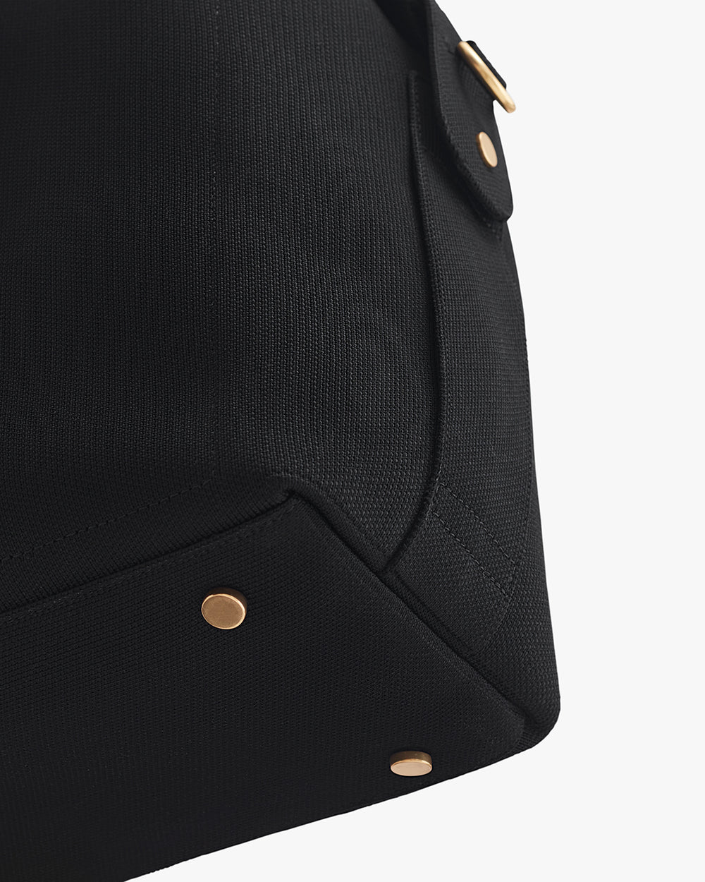 Close-up of a travel bag with metal studs and a pocket flap.