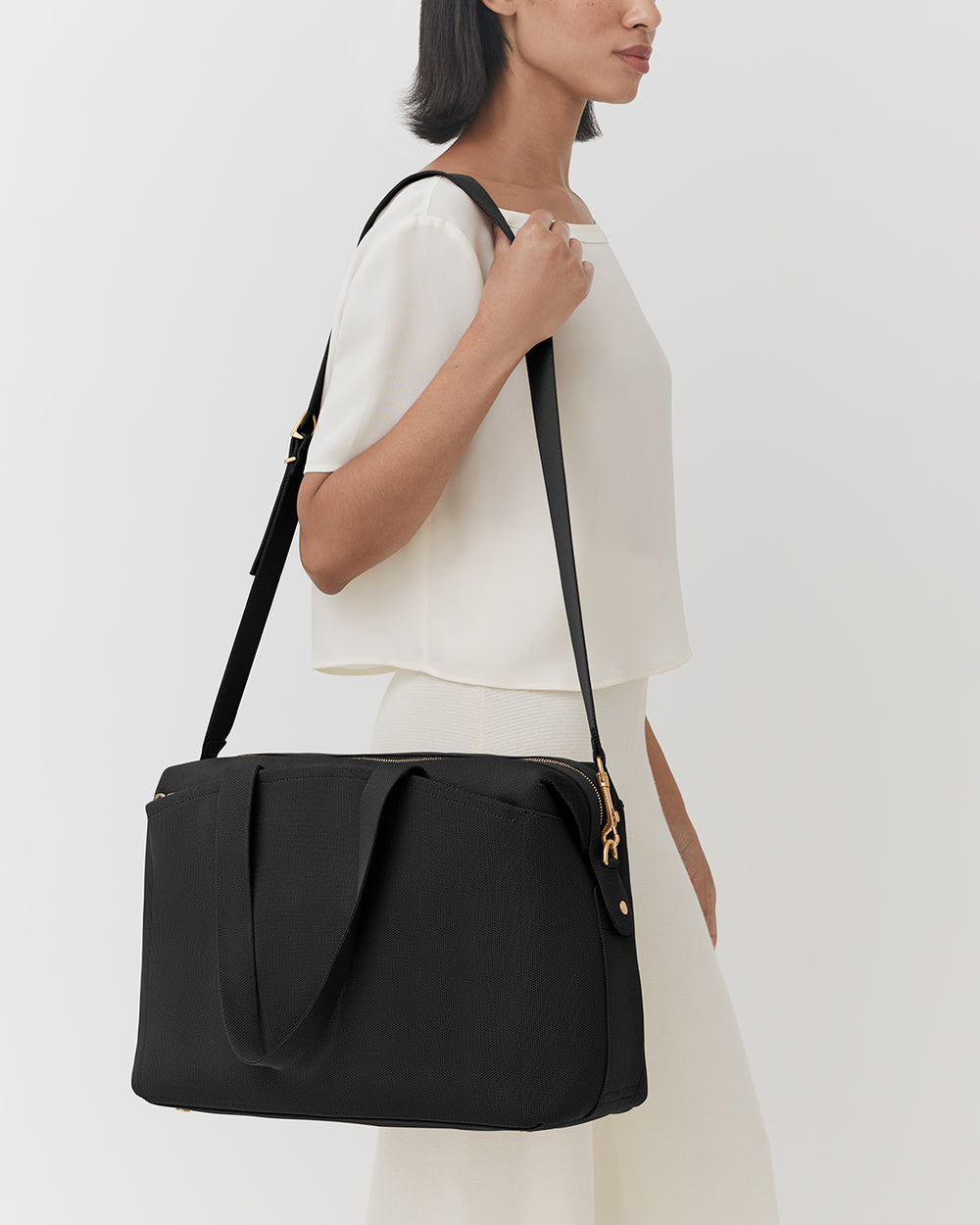 Person carrying a travel bag on their shoulder.
