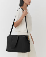 Person carrying a travel bag on their shoulder.