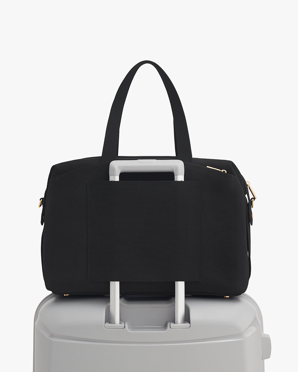 Travel bag on top of rolling suitcase with handle through strap