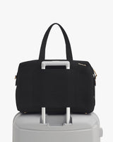 Travel bag on top of rolling suitcase with handle through strap