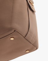 Close-up of a travel bag with metal studs and a pocket flap.