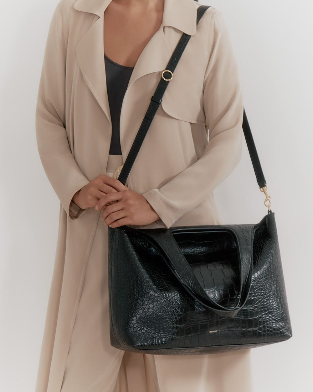 Person holding a handbag with a shoulder strap, wearing a coat