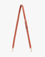 Adjustable strap with metal clasps and loops displayed against a plain background.