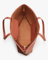 Top view of an open, empty handbag with two handles and inner compartments.
