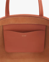 Close-up of a handbag with a front pocket and brand logo.