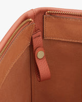 Close-up view of a leather bag with zipper and snap button details.