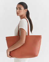 Woman holding a large tote bag on her shoulder.