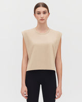 Woman in sleeveless top and pants standing facing forward.