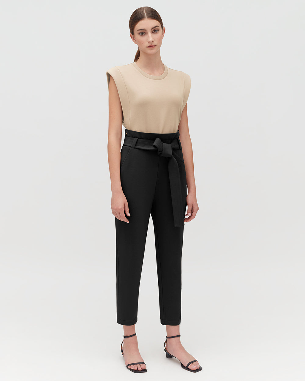Cropped Tank Woman standing in a sleeveless top and belted trousers