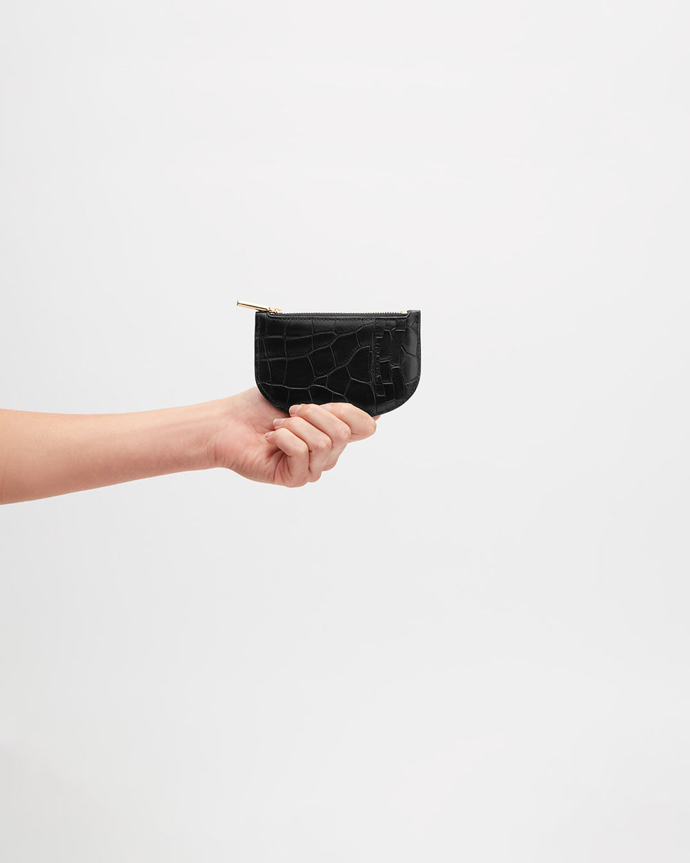 Hand holding a small zippered pouch against a plain background.
