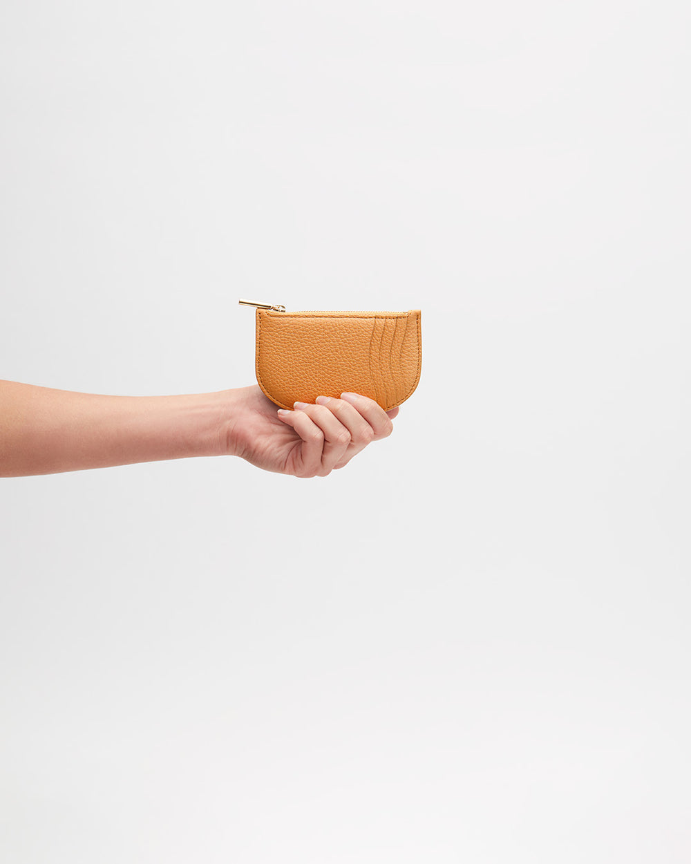 Hand holding a small purse against a plain background.