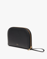 Handbag with zipper and wrist strap standing upright against a plain background