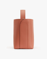Vertical leather bag with a loop on top against a plain background.