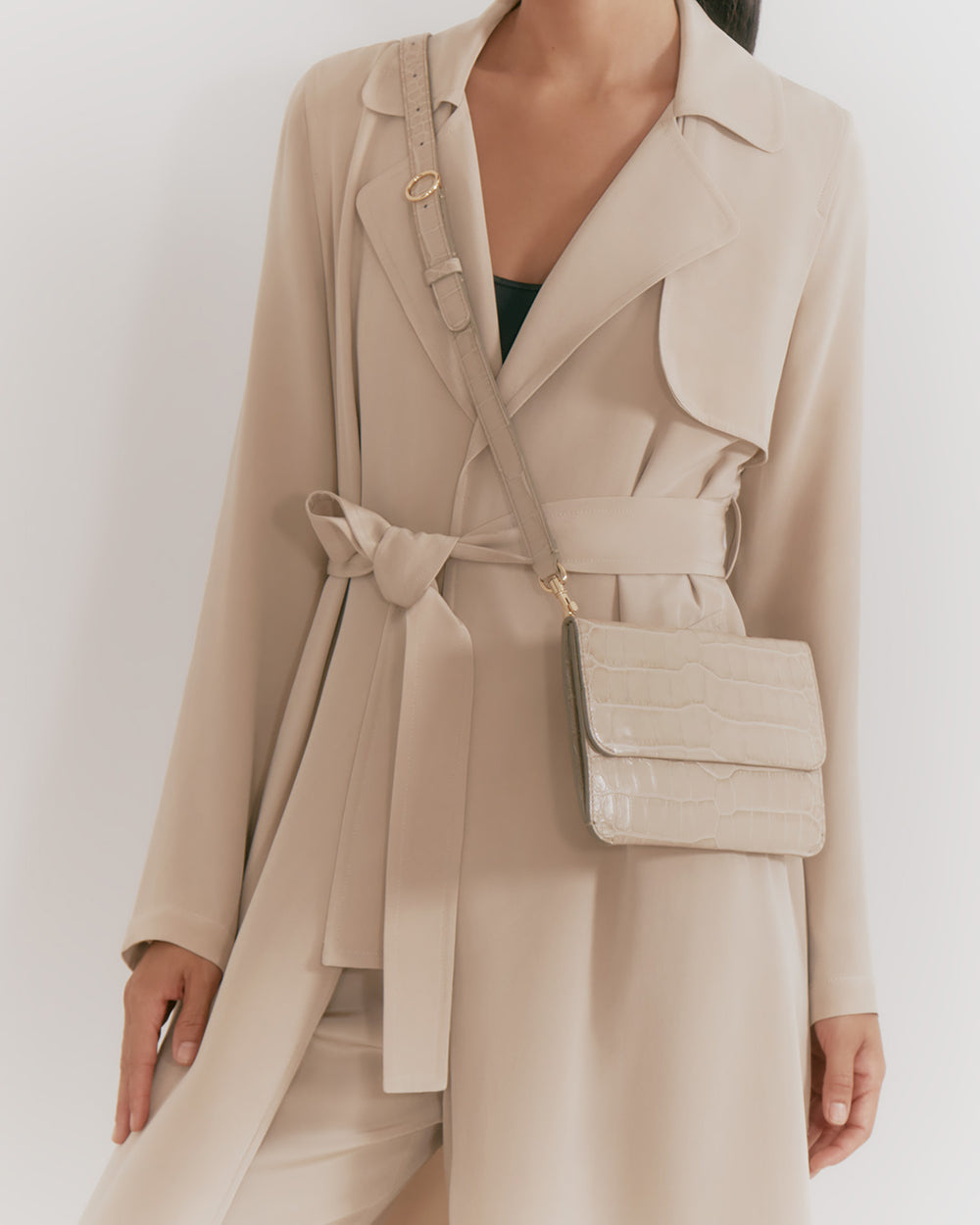 Person in a trench coat wearing a crossbody bag.