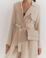 Person in a trench coat wearing a crossbody bag.