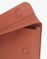 Close-up of a leather bag with flap closure and snap buttons.