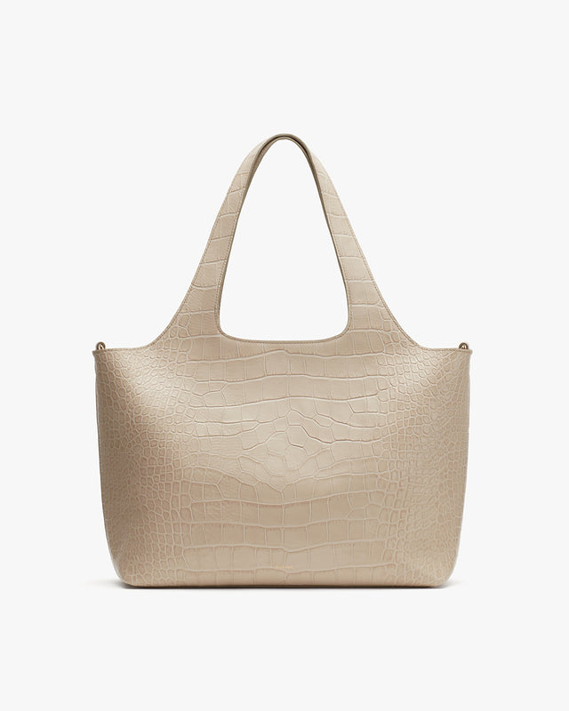 Handbag with two handles and textured surface.