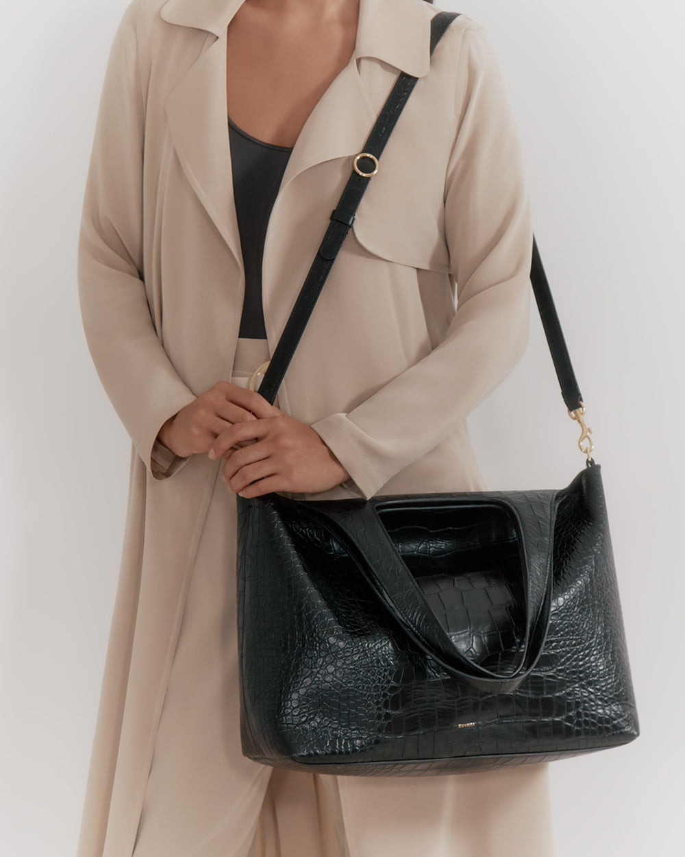 Person holding a large handbag with a shoulder strap.