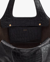 Close-up of a croc-embossed leather handbag with a visible brand label.