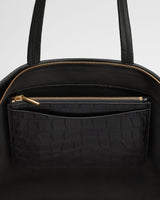 Handbag with outer pocket and top zipper closure.