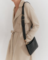 Woman wearing a trench coat carrying a shoulder bag.