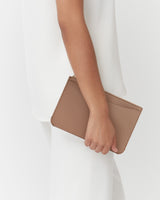 Person holding a small clutch bag by their side.