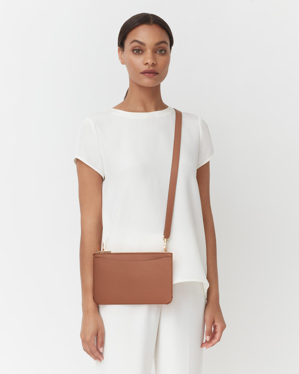 System Zipper Pouch Woman standing with a crossbody bag, looking at the camera.