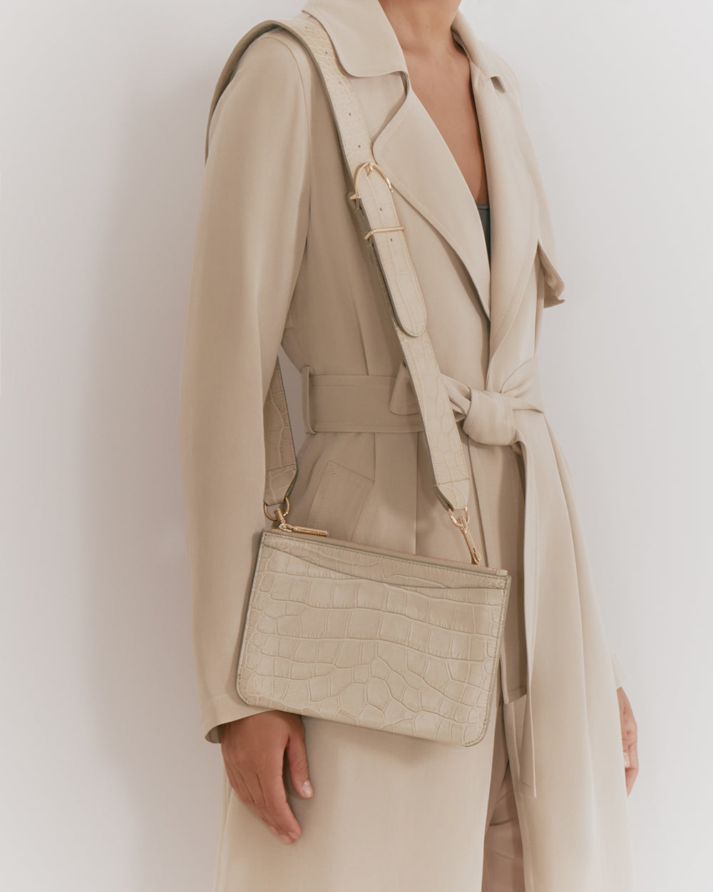 Woman wearing a trench coat carrying a shoulder bag.