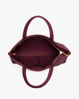Open handbag with two handles and visible zipper.
