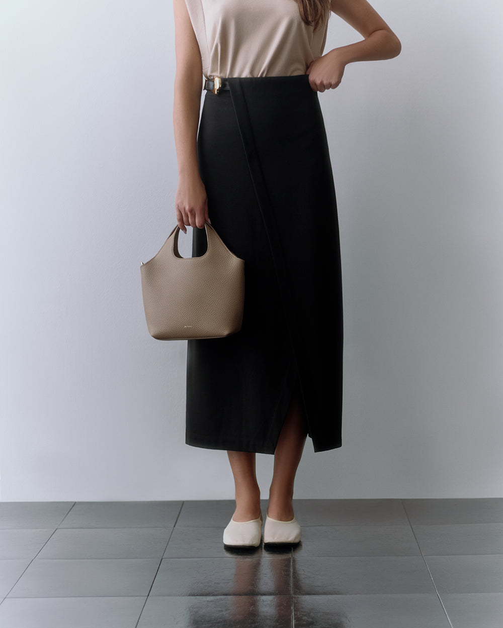 Mini System Tote Person in a sleeveless top and wrap skirt carrying a handbag