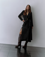 Woman in belted blazer, skirt, croc-embossed leather boots, and necklace.