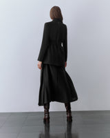 Model wearing blazer, skirt, and boots. standing facing away