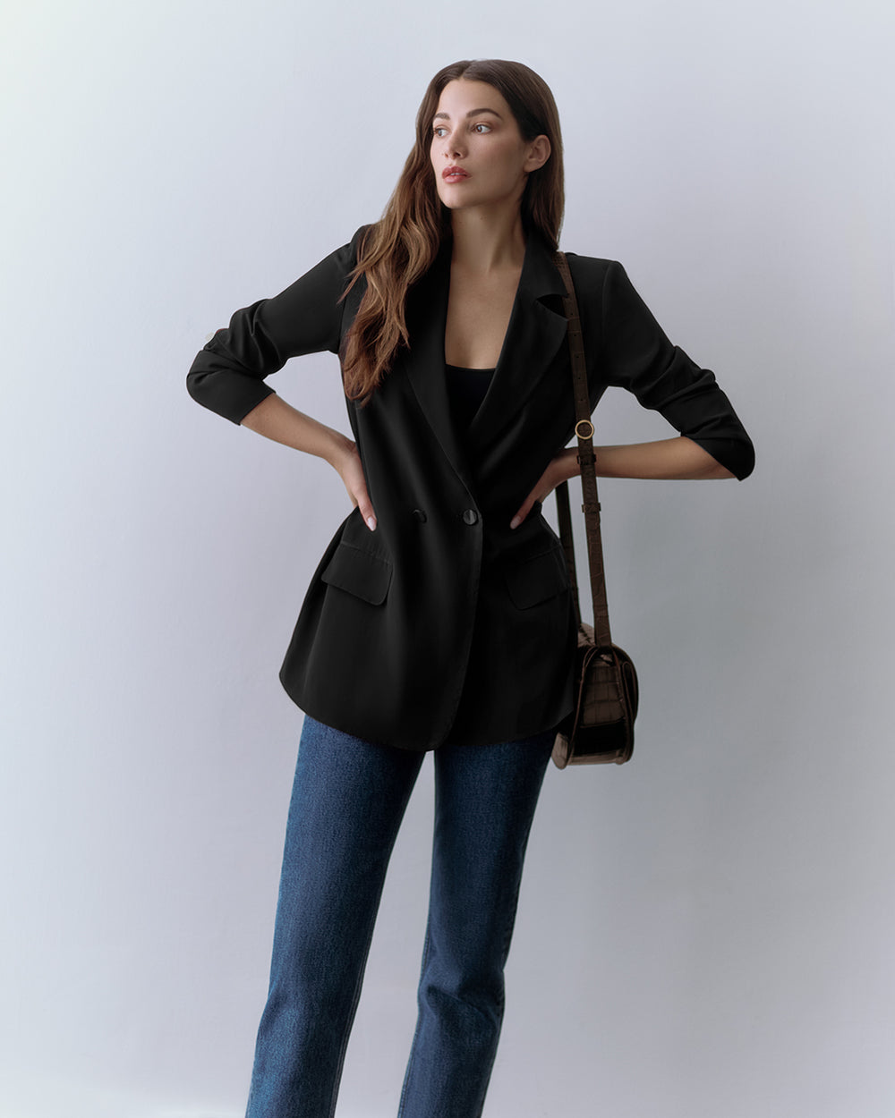 Person wearing a blazer, jeans, and a croc-embossed leather crossbody bag.