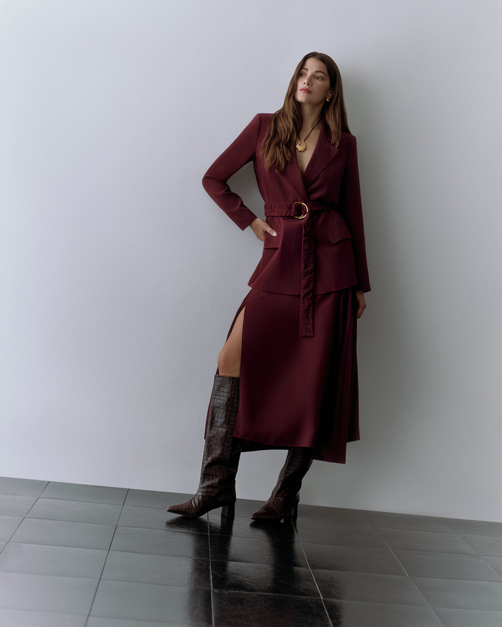 Woman in belted red blazer, red slit skirt, croc-embossed leather boots, and necklace.